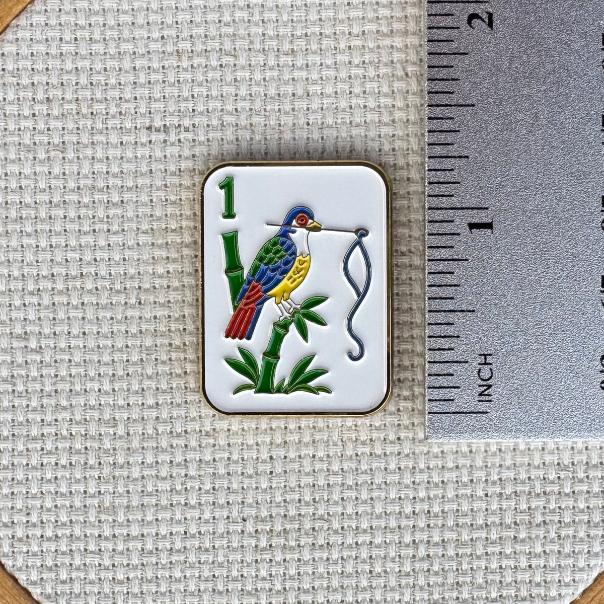 Birdie Bam mahjong tile needle minder featuring a colorful bird design enamel needle minder with gold color trim, magnetic accessory for cross stitch, needlepoint, embroidery, quilting and sewing.