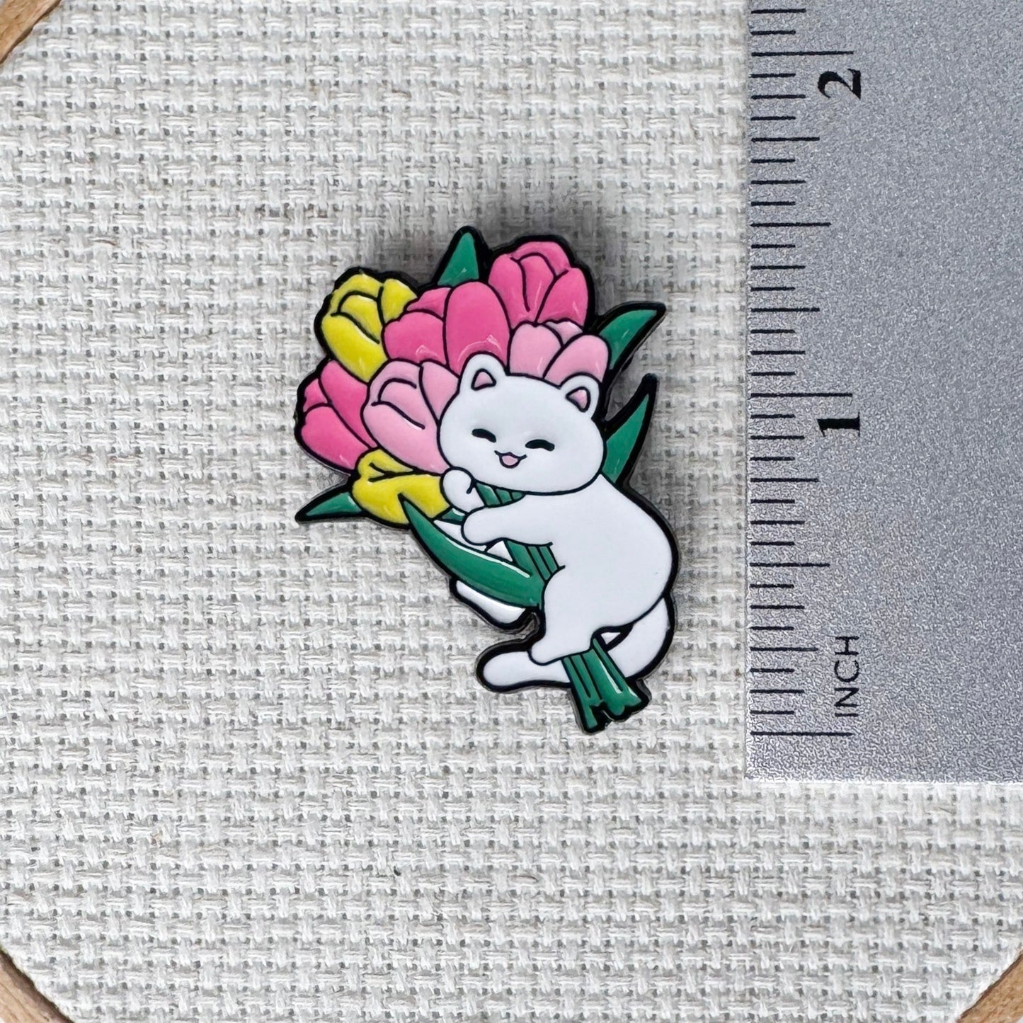 White cat holding pink and yellow tulips needle minder – magnetic enamel holder for cross stitch, embroidery, needlepoint or sewing.