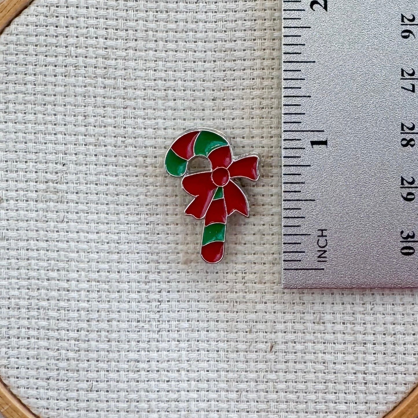 Green and red candy cane magnetic needle minder – festive enamel accessory for cross stitch, embroidery, and needlepoint – holiday stitching gift with classic Christmas candy design.