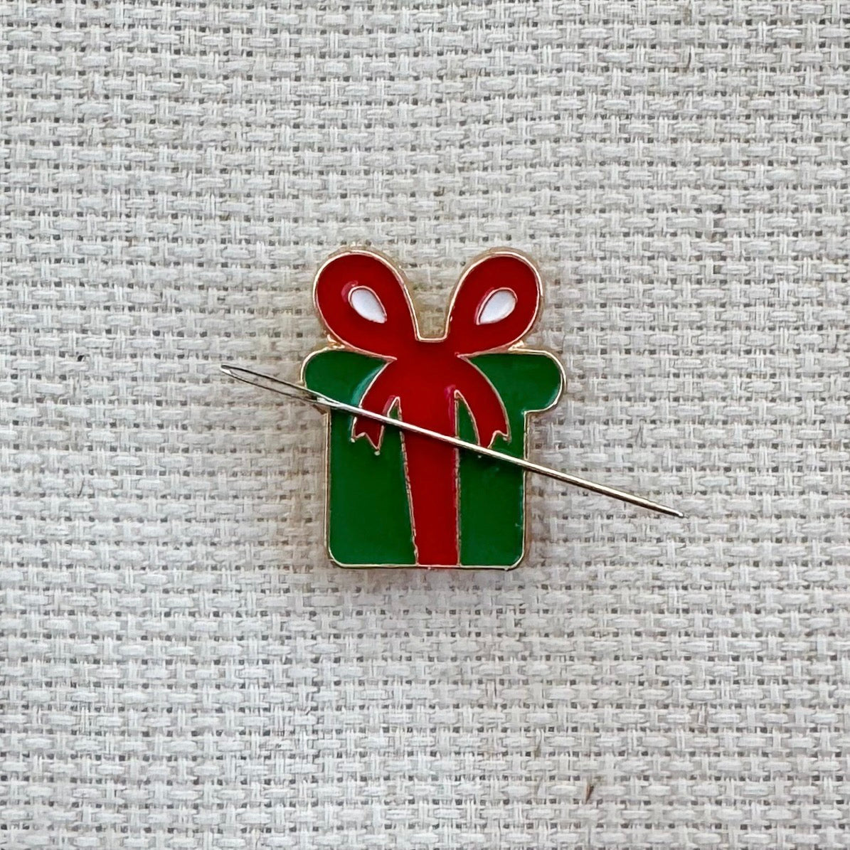 Christmas green present with red bow magnetic needle minder – festive enamel accessory for cross stitch, embroidery, and needlepoint – holiday gift box design for stitchers and crafters.