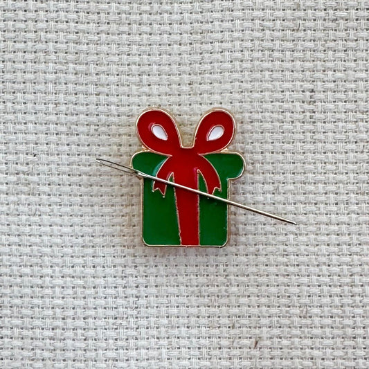 Christmas green present with red bow magnetic needle minder – festive enamel accessory for cross stitch, embroidery, and needlepoint – holiday gift box design for stitchers and crafters.