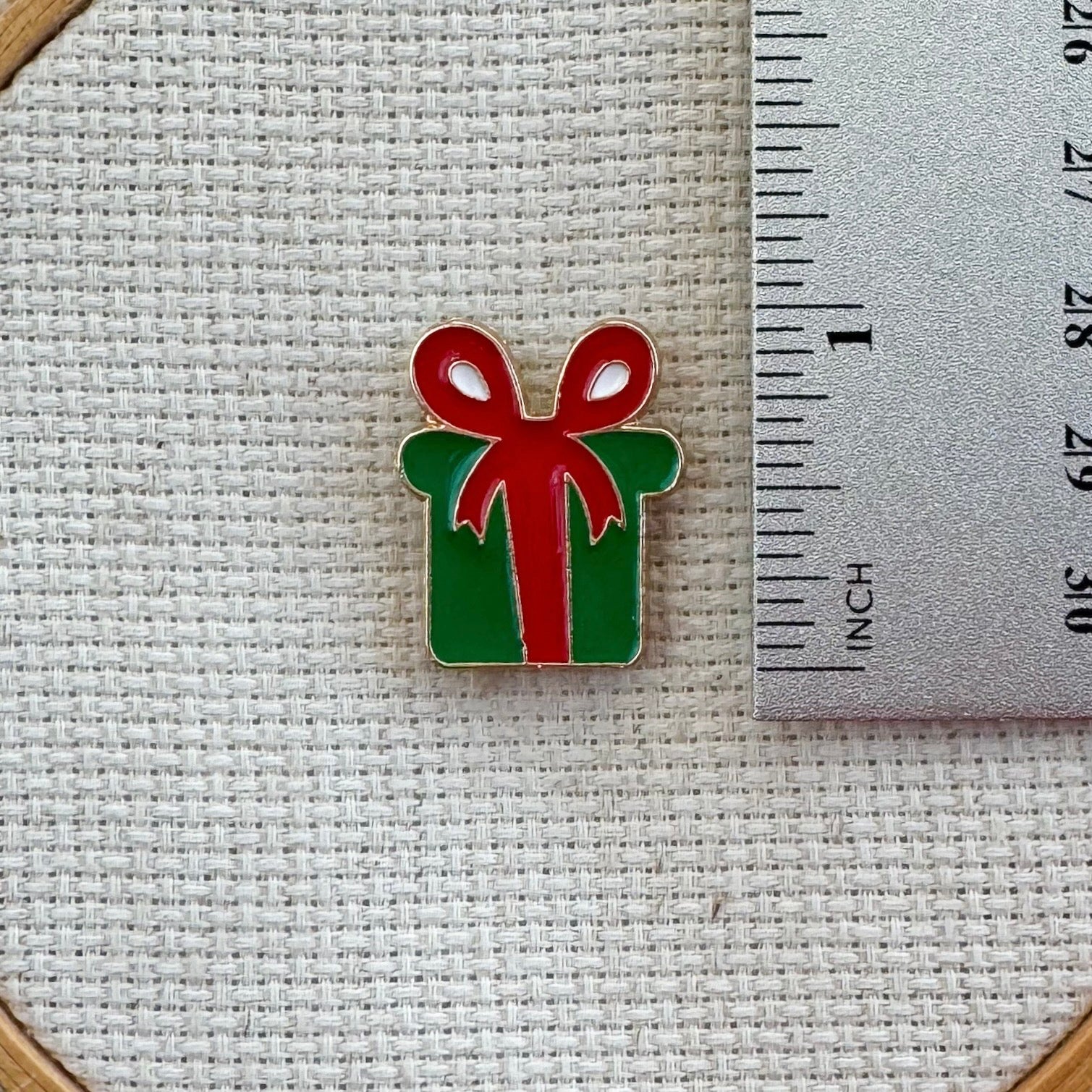 Christmas green present with red bow magnetic needle minder – festive enamel accessory for cross stitch, embroidery, and needlepoint – holiday gift box design for stitchers and crafters.