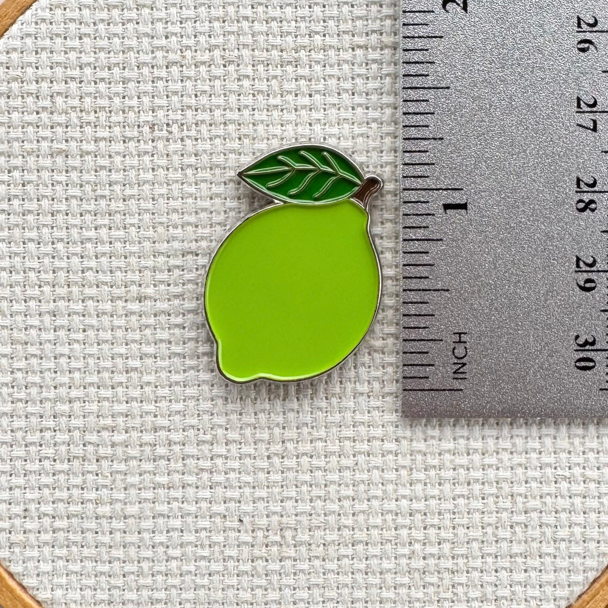 Green lime needle minder shown with ruler for size measurement, approximately 1.25 inch.