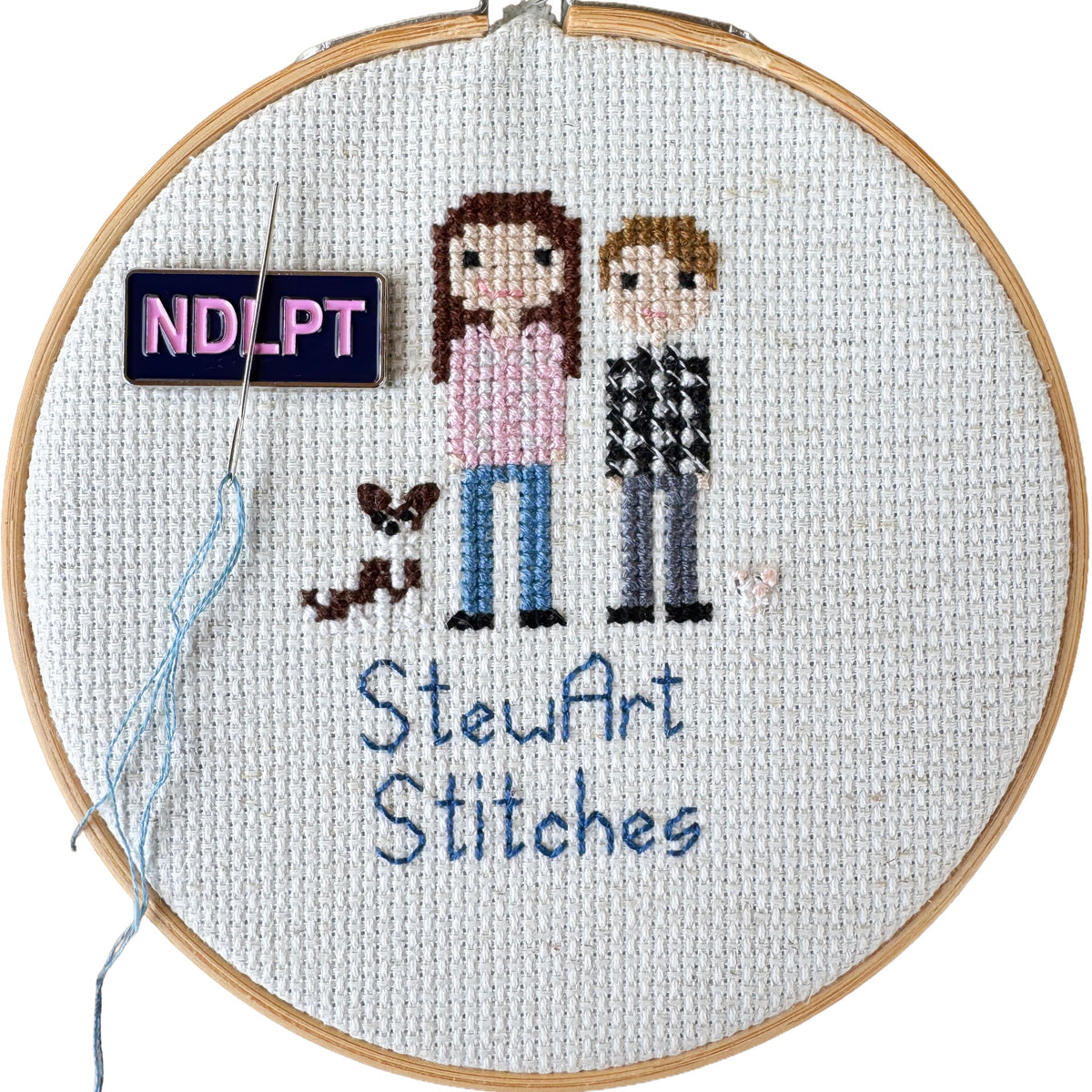 NDLPT magnetic enamel needle minder holding a needle on a cross stitch canvas while stitching.