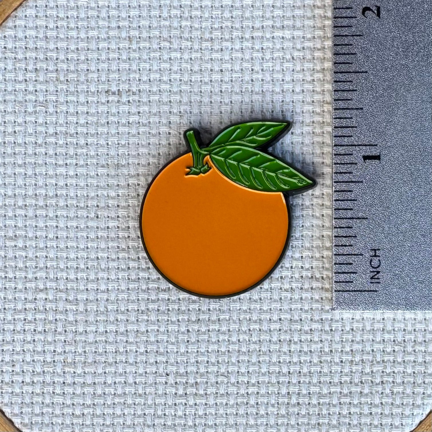 Orange needle minder shown with ruler for size measurement, approximately 1.25 inch.