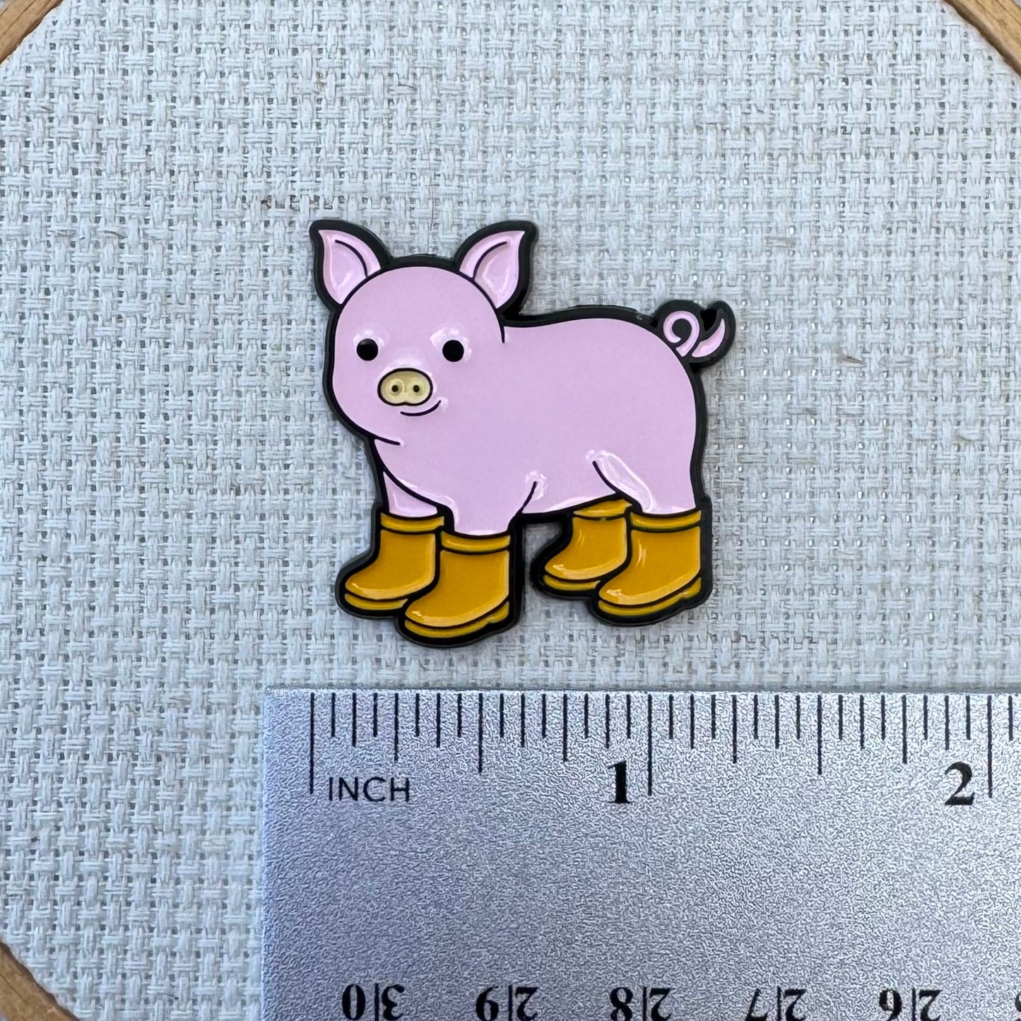 Pig with Yellow Boots Enamel needle minder shown with ruler for size measurement, approximately 1.25 inch.