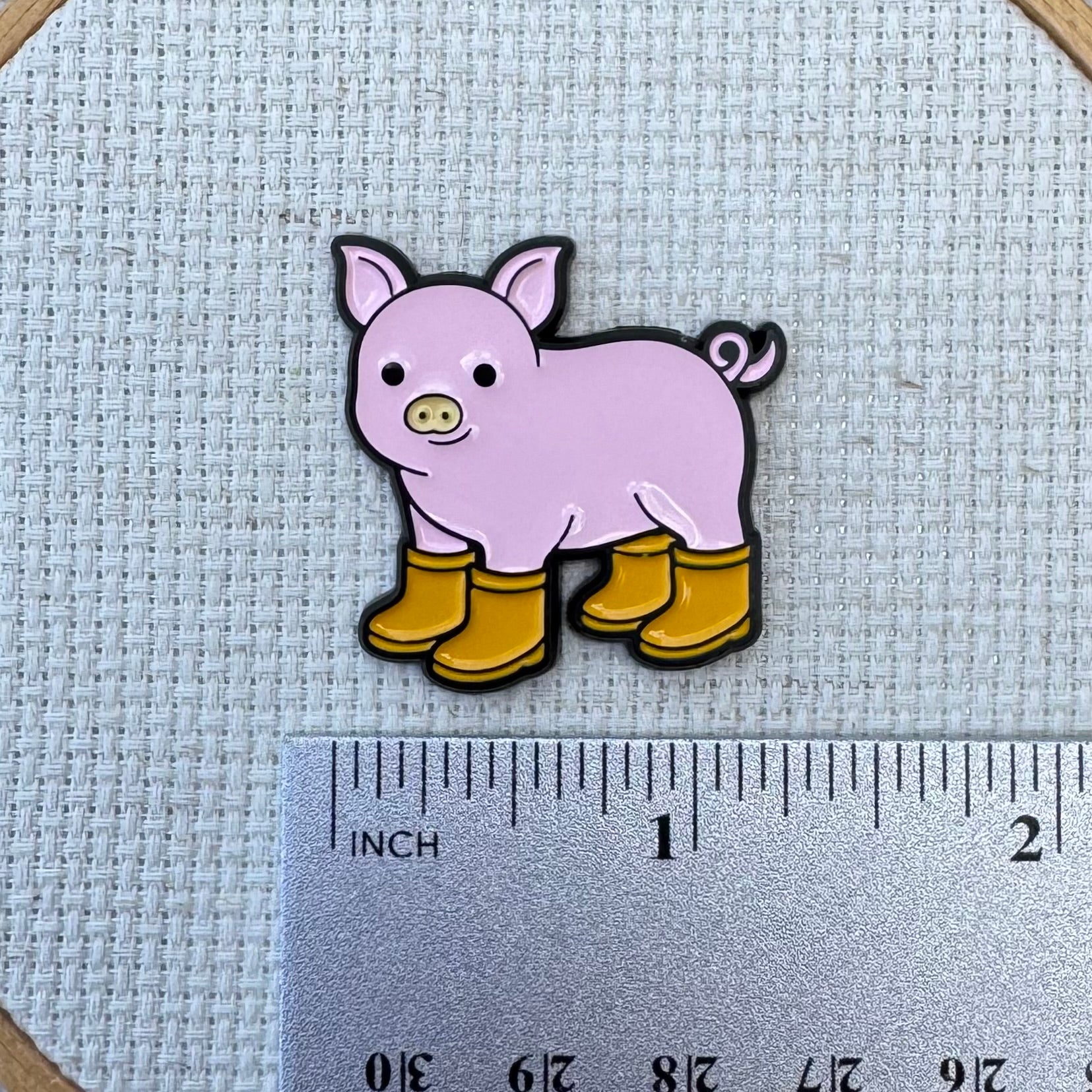 Pig with Yellow Boots Enamel needle minder shown with ruler for size measurement, approximately 1.25 inch.