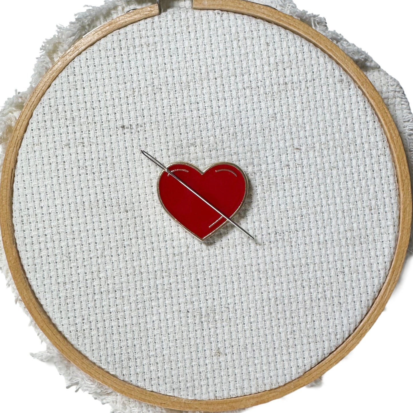 Red heart shaped magnetic enamel needle minder for cross stitch, embroidery, needlepoint and sewing projects.