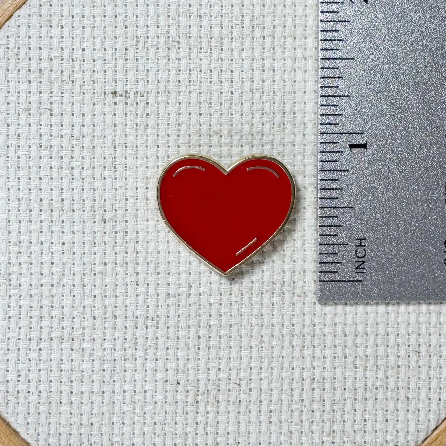 Red heart shaped magnetic enamel needle minder for cross stitch, embroidery, needlepoint and sewing projects.