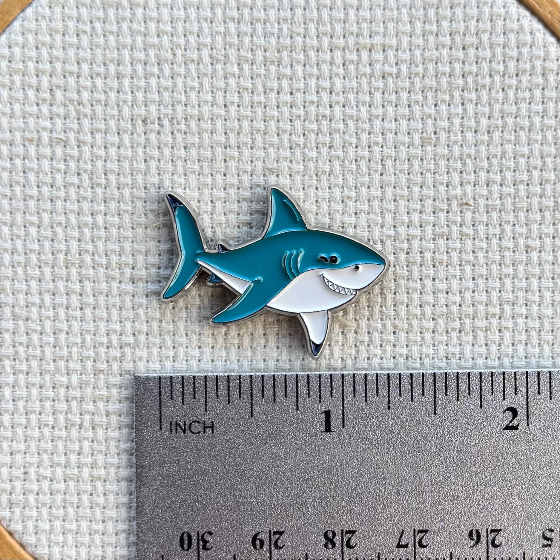 Shark needle minder shown with ruler for size measurement, approximately 1.25 inch.
