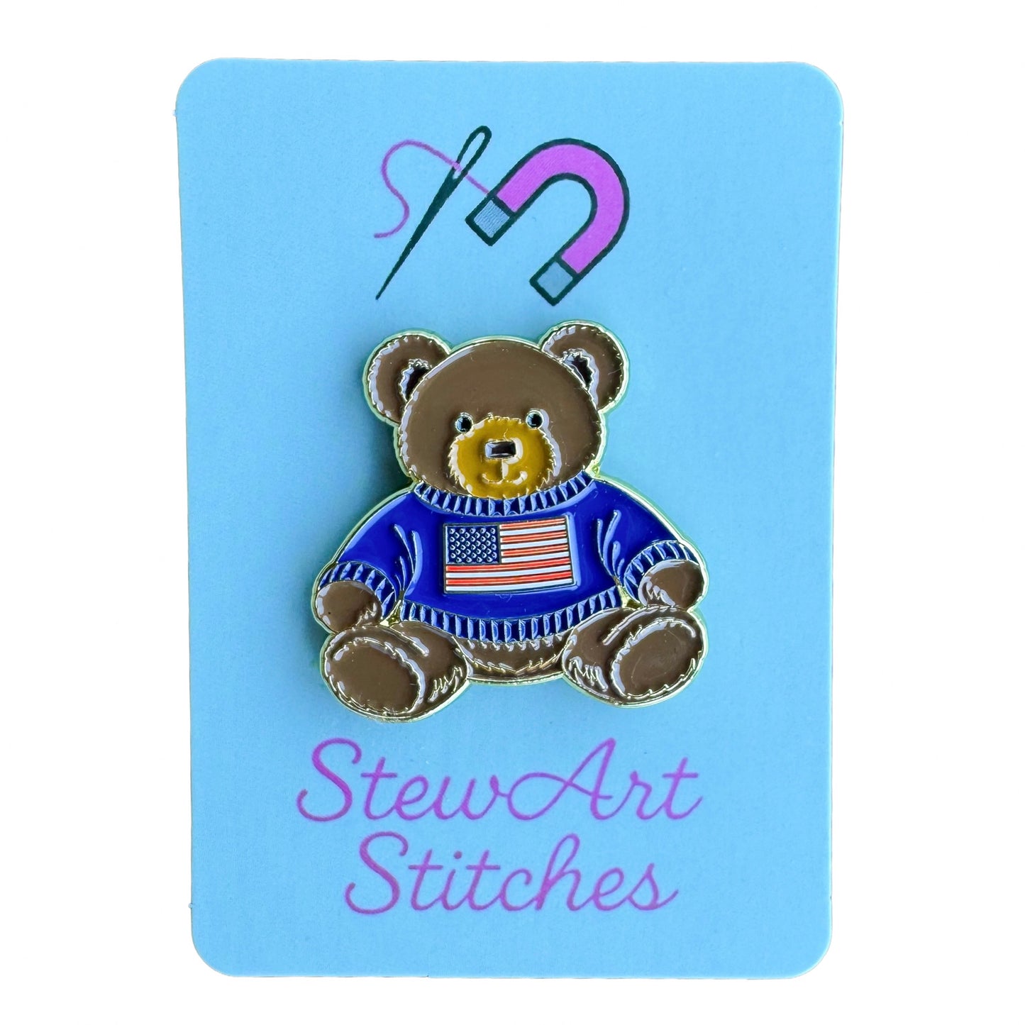 Teddy bear enamel needle minder wearing a blue sweater with an American flag, magnetic needle holder for cross stitch, needlepoint, embroidery, quilting, sewing and other stitching projects.