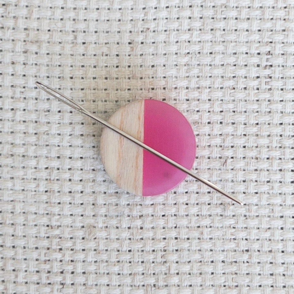 Circle shaped magnetic needle minder with pink resin and natural wood – perfect for cross stitch, embroidery, needlepoint, quilting, and hand sewing. A unique and functional needle holder for stitchers and crafters.