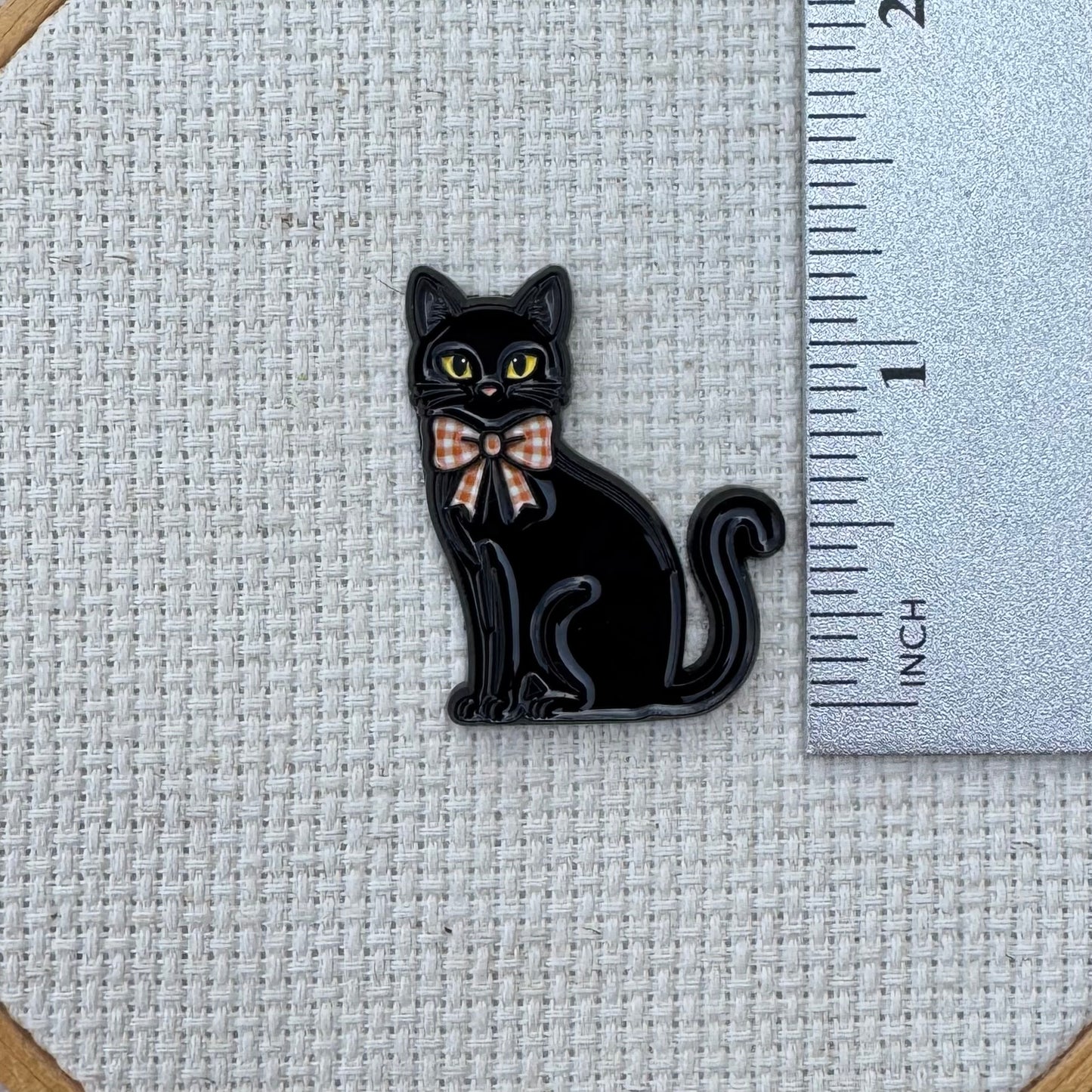 Black cat needle minder shown with ruler for size measurement, approximately 1.25 inch.