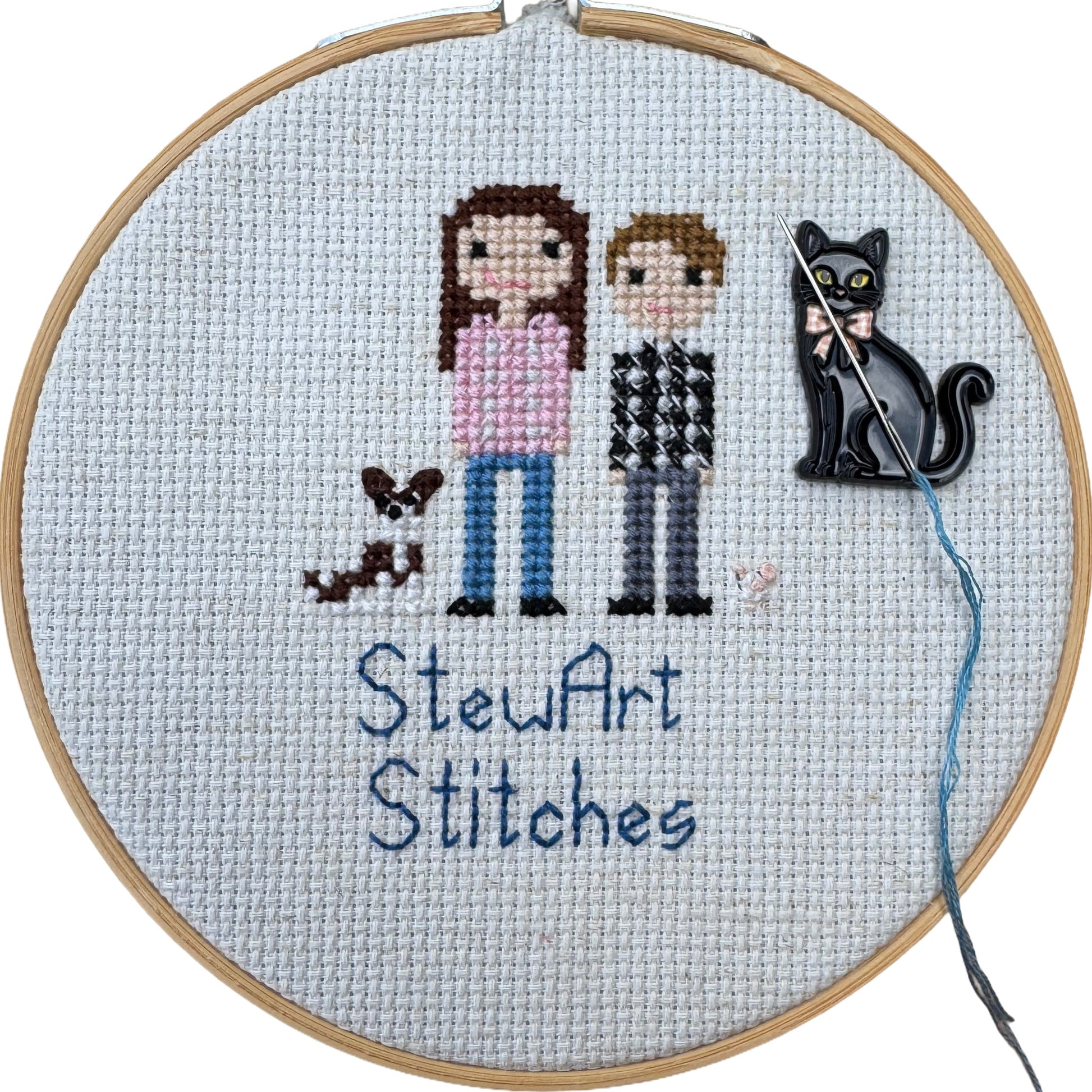 Black cat enamel magnetic needle minder holding a needle on a needlepoint canvas while stitching.