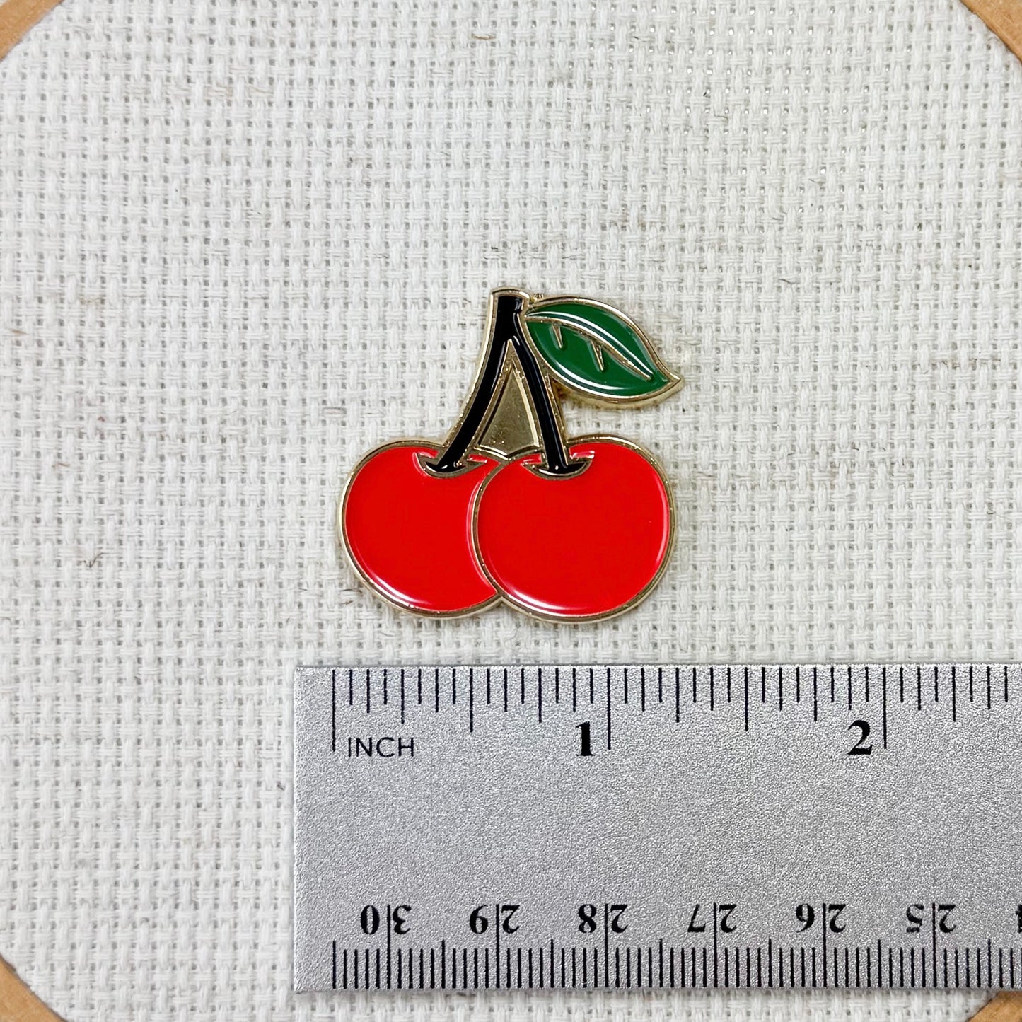 Red cherry needle minder with strong magnet for stitching.