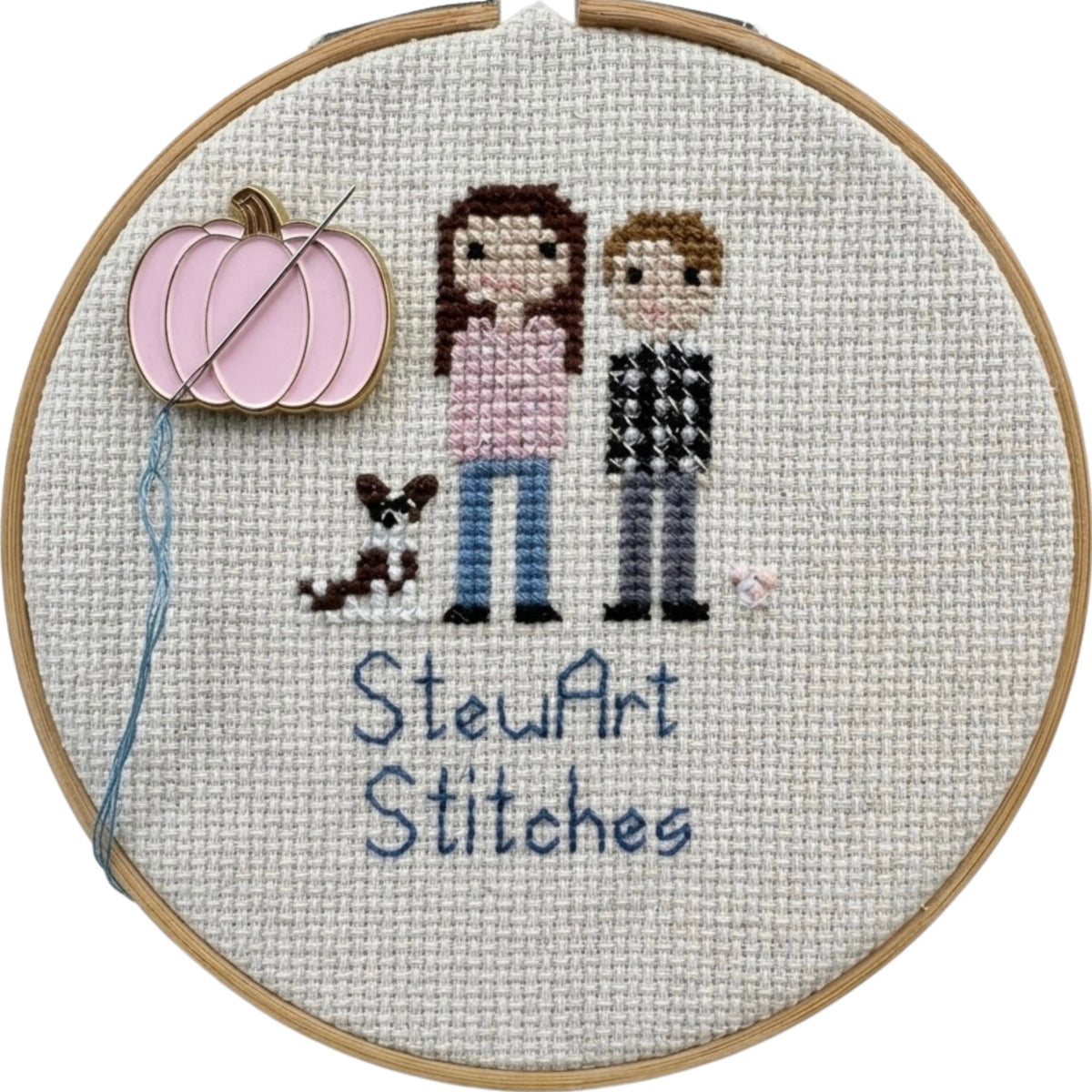 Pink pumpkin needle minder holding a needle on a needlepoint canvas while stitching.