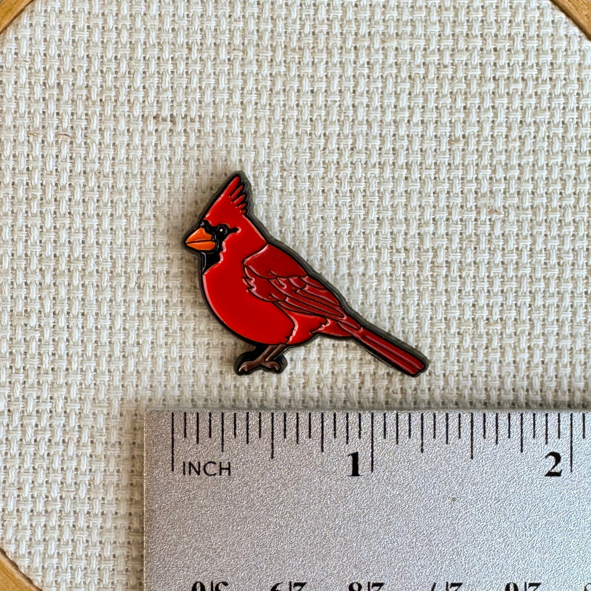 Cardinal needle minder shown with ruler for size measurement, approximately 1.25 inch.