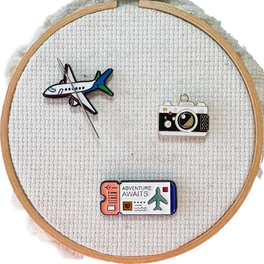 Airplane, ticket and camera magnetic needle minders – travel themed enamel accessory for cross stitch, embroidery, and needlepoint – fun stitching gift for travelers and adventure lovers.